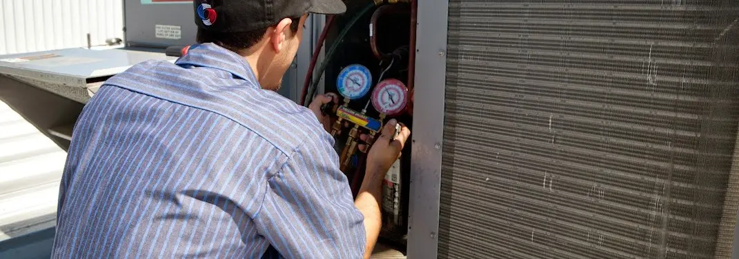 HVAC technician servicing a condenser unit in Charlton
