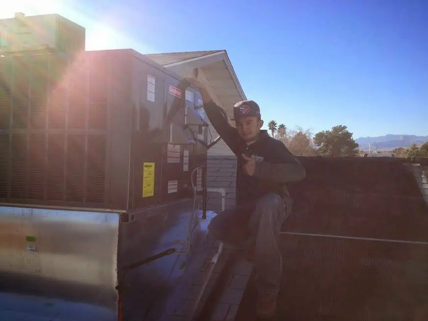 HVAC technician performing Air Duct Cleaning on a rooftop unit in Charlton